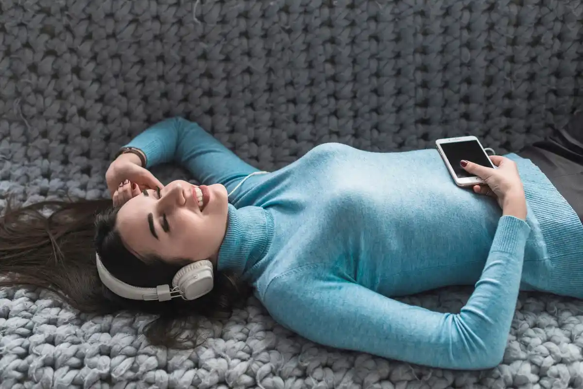 woman listening to audio with headphones in bed sleep learning