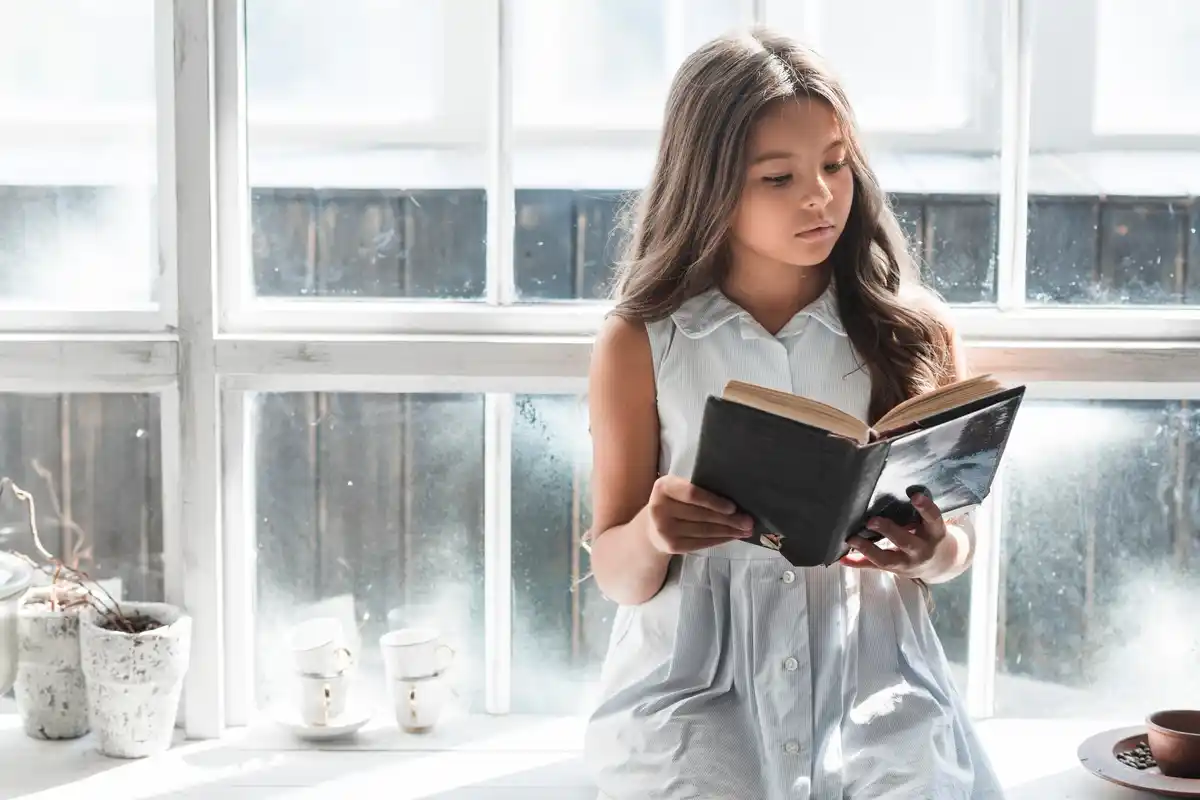 woman holding an old hardcover book near window, soft morning light