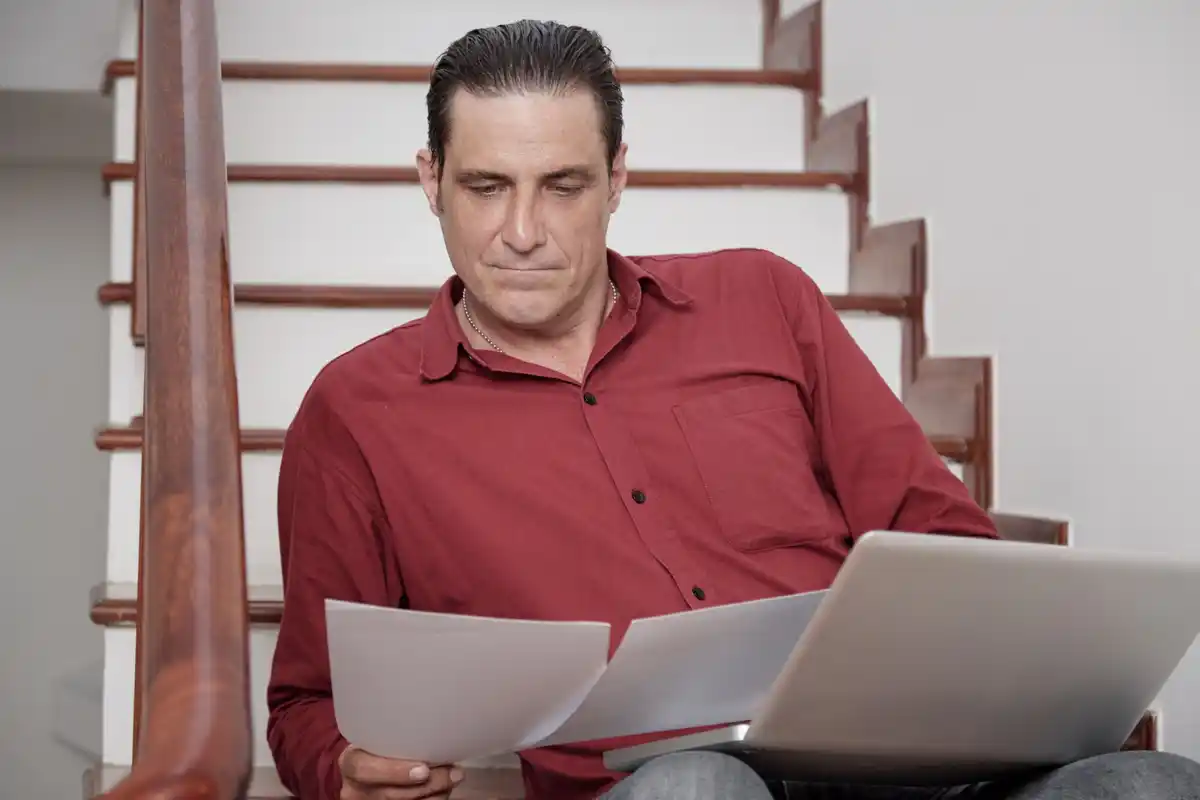 Dutch person searching for contract on laptop, looking confused