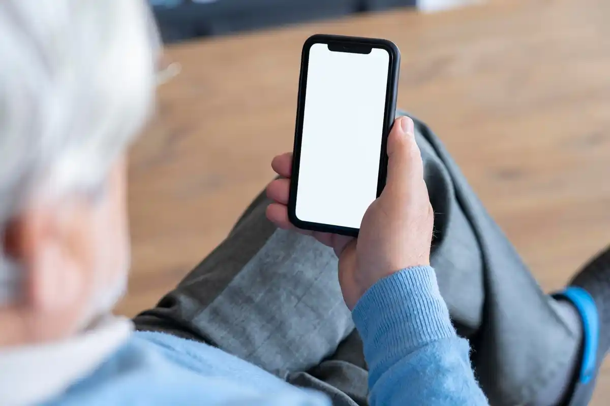 elderly hands holding smartphone with large text