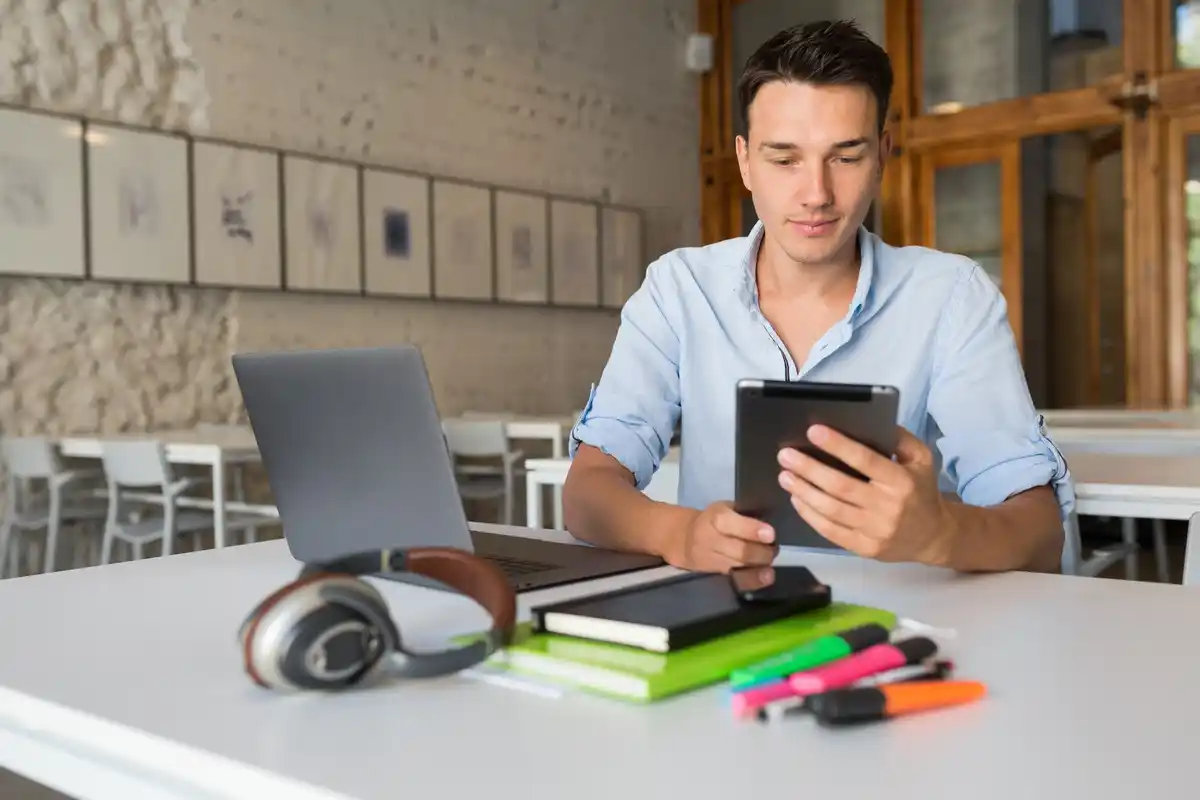 student multitasking with phone and laptop desk dutch