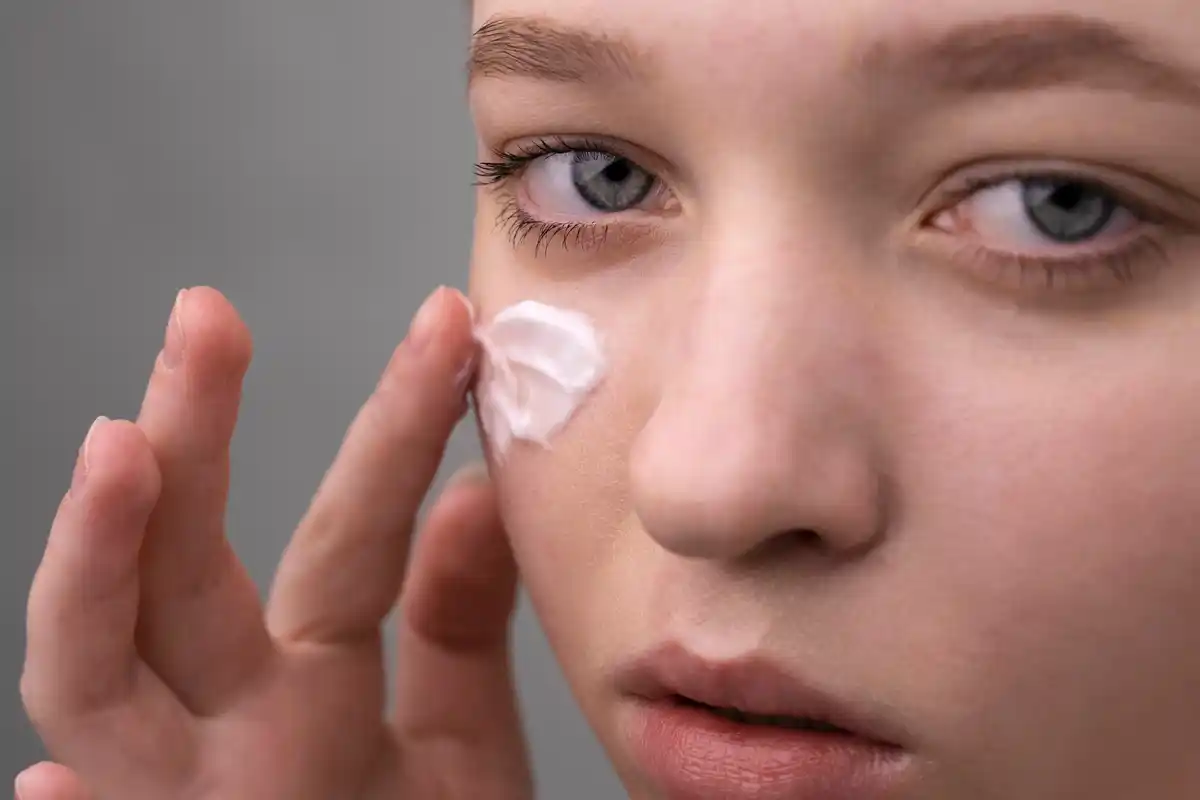 woman applying eye cream gently under eyes close up