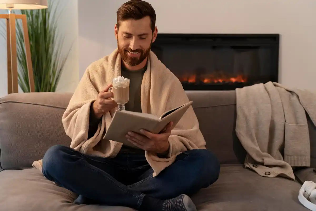 young adult reading book at home evening cup of tea