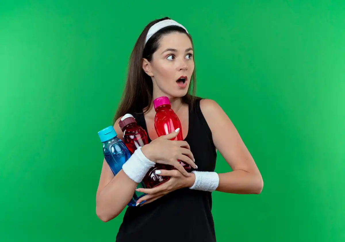Dutch sports drink close-up, athletic woman holding quirky bottle, Holland gym