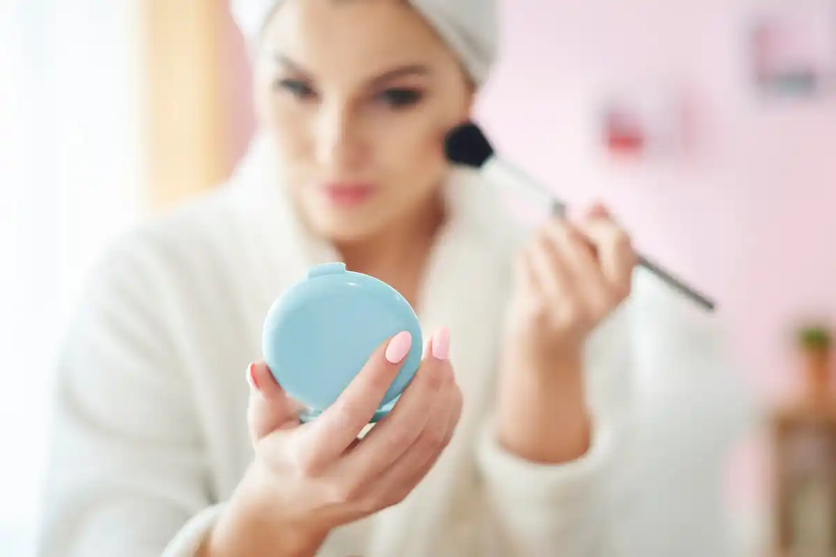 woman adding contact lens solution to mascara tube bathroom mirror