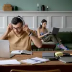 overwhelmed person working at cluttered desk with digital distractions