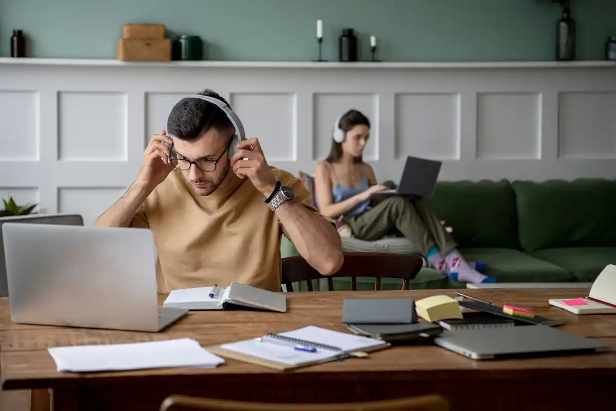 overwhelmed person working at cluttered desk with digital distractions