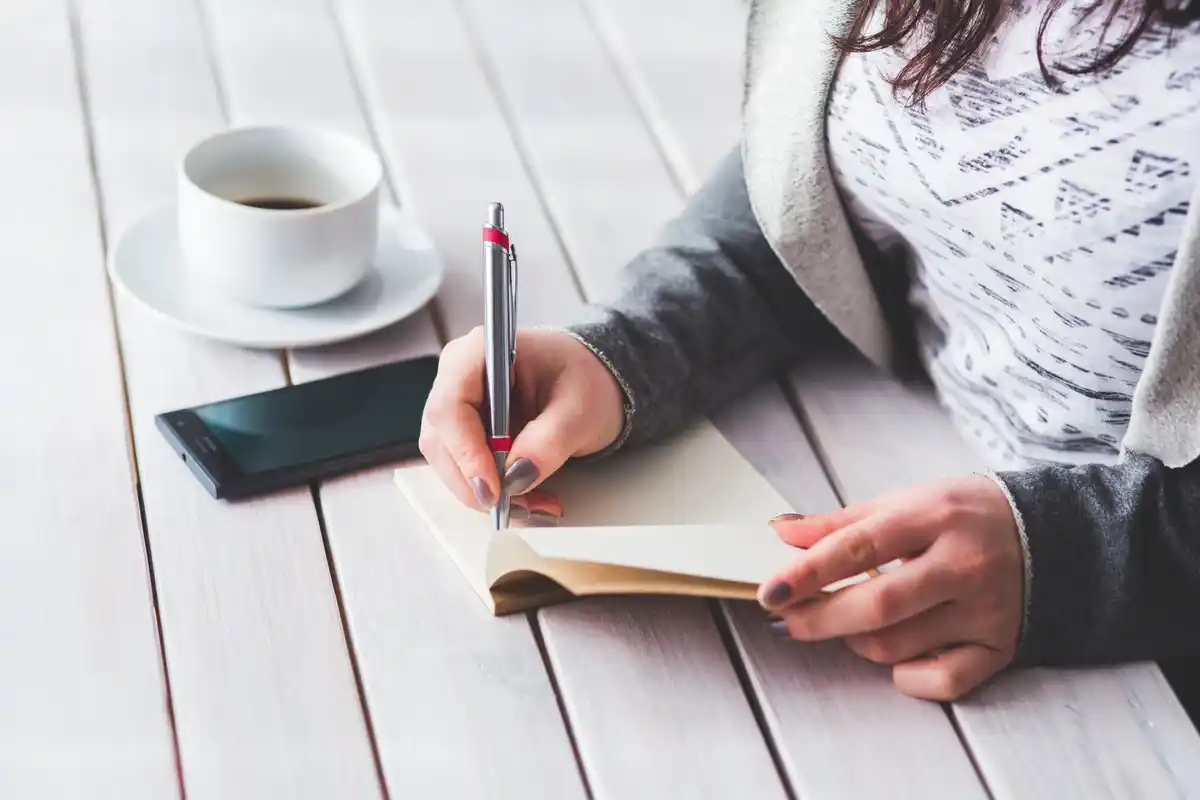 person crossing off tasks on a planner with morning light