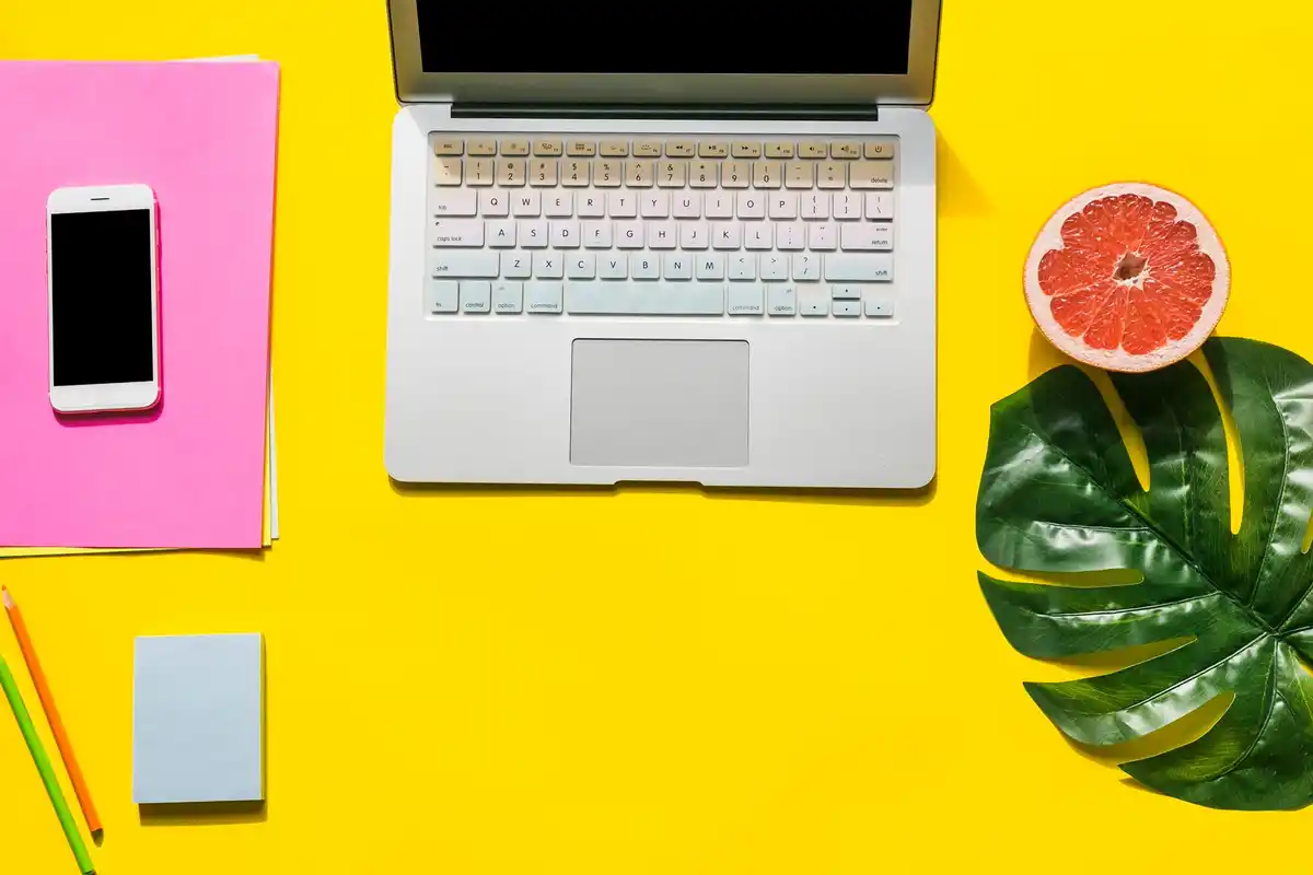 yellow notebook on desk next to laptop