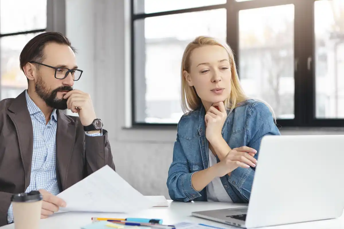 two people silently sitting at table looking away awkward dutch office