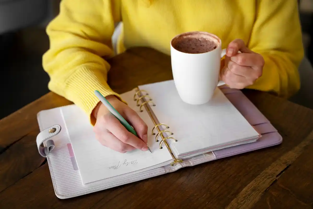 dutch hands writing in paper planner at cozy table