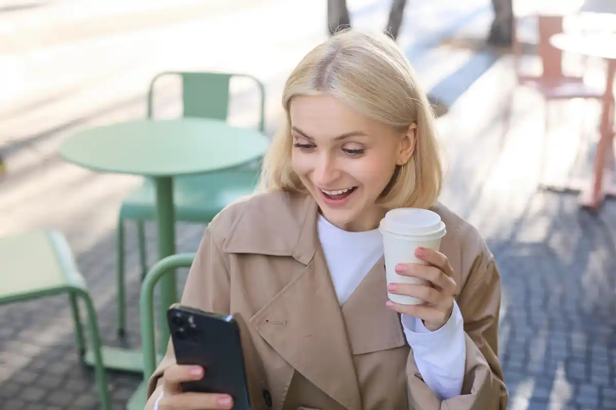 Young Dutch person checking mobile banking app while drinking coffee in a café