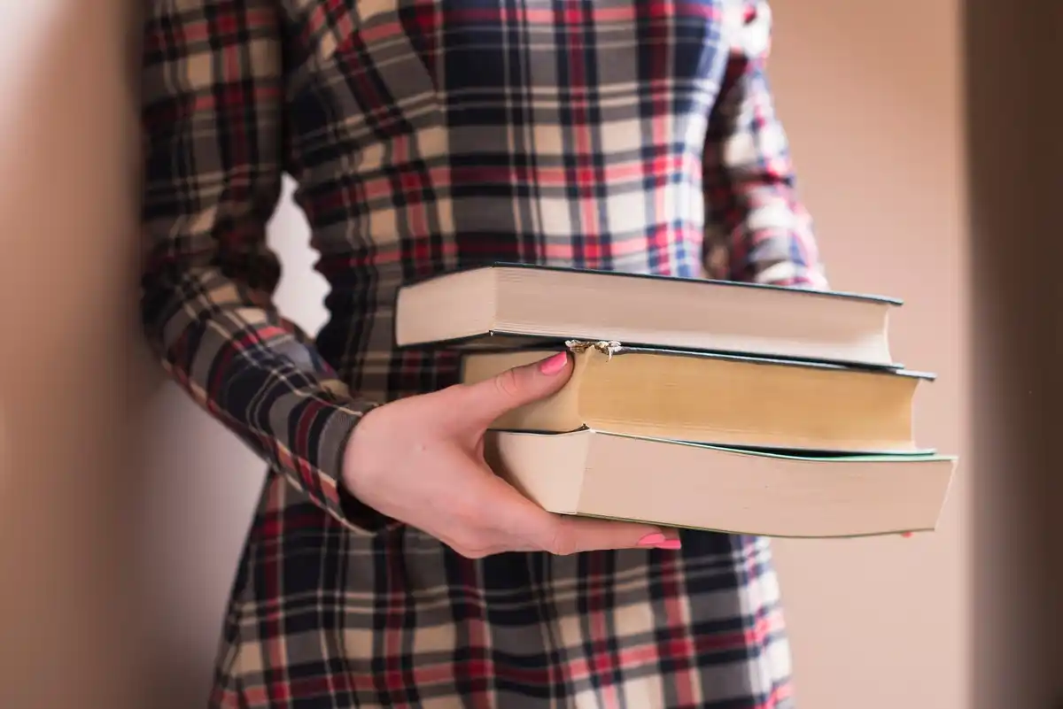dutch student holding pile of old schoolbooks indoors