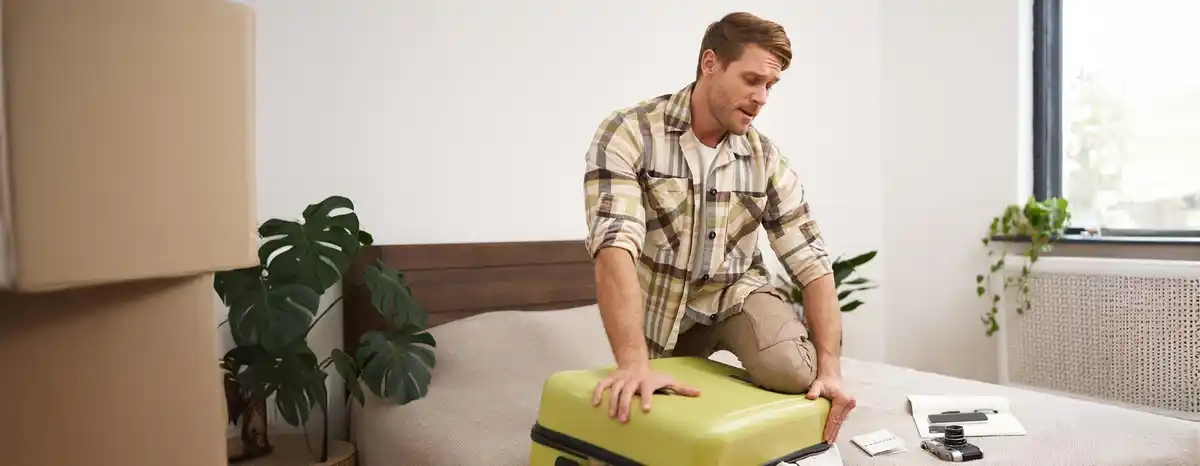 Dutch man packing suitcase rolling clothes minimal travel light cheerful