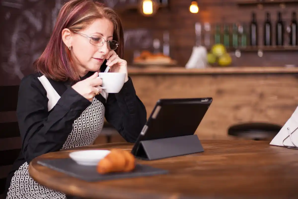 young adult learning with phone and notebook at a cozy cafe
