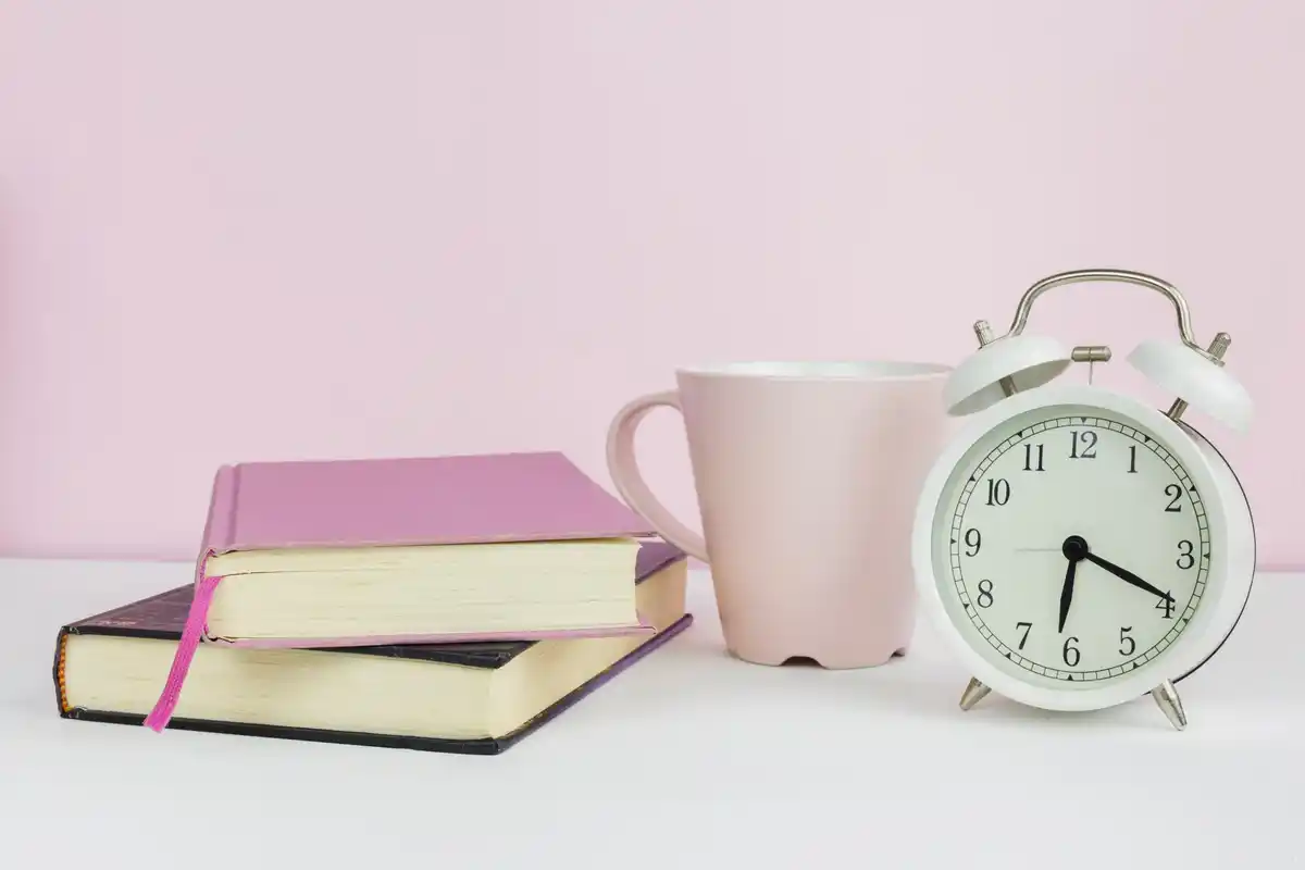 clock and study materials on a wooden desk daylight relaxed study time