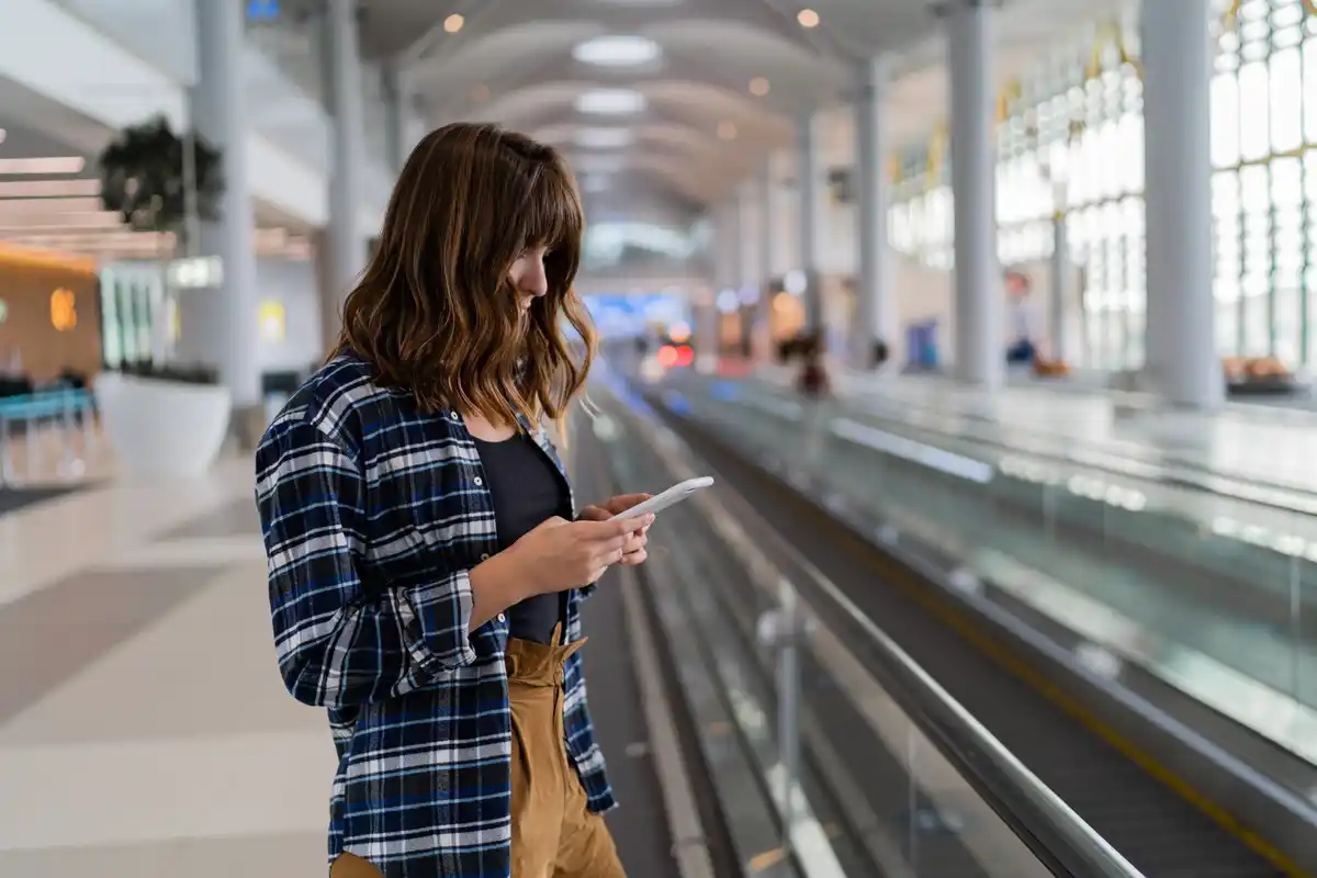 traveler using smartphone to check exchange rates at airport