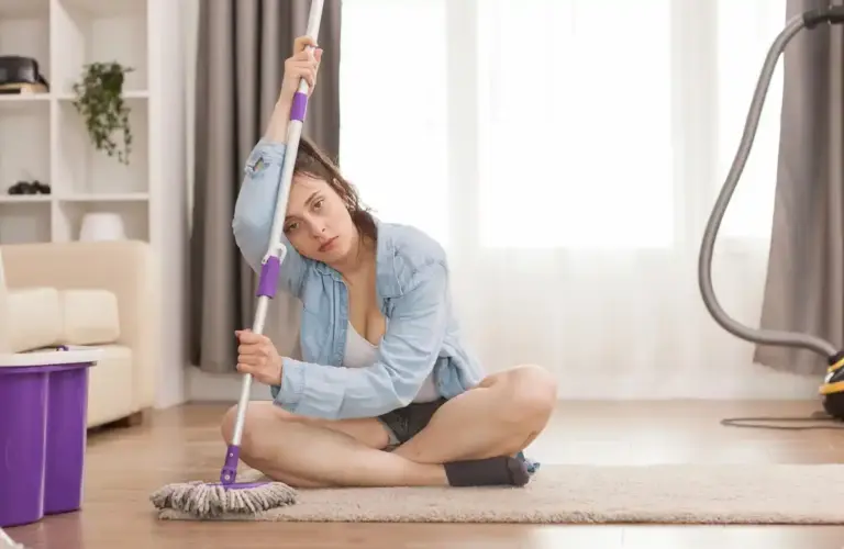 Dutch person sweeping with traditional broom in living room