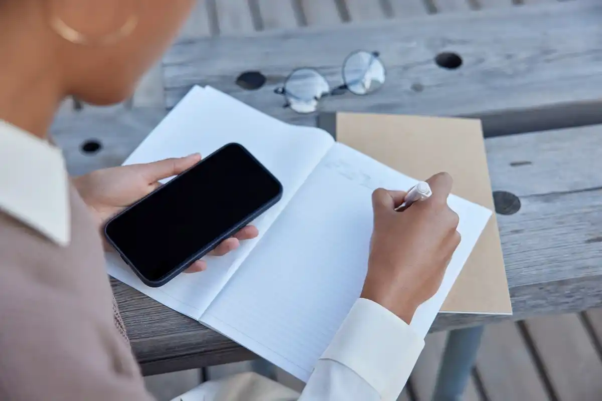 handwritten to-do list next to smartphone with productivity apps