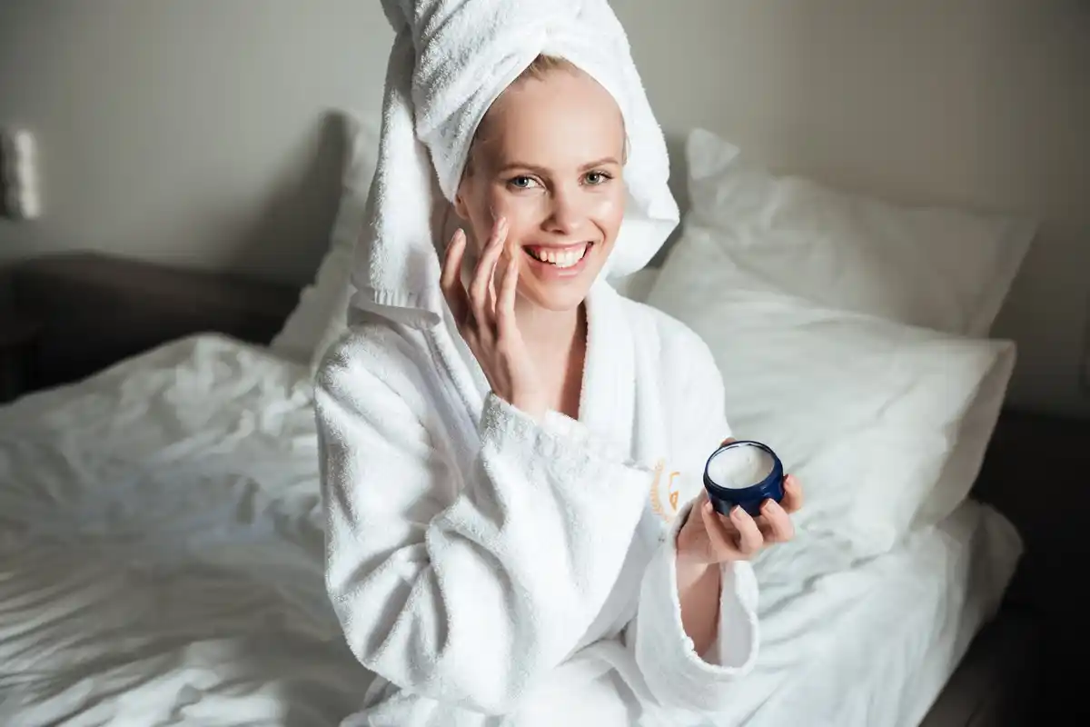 woman applying vaseline on face at night, cozy bedroom, natural skin care