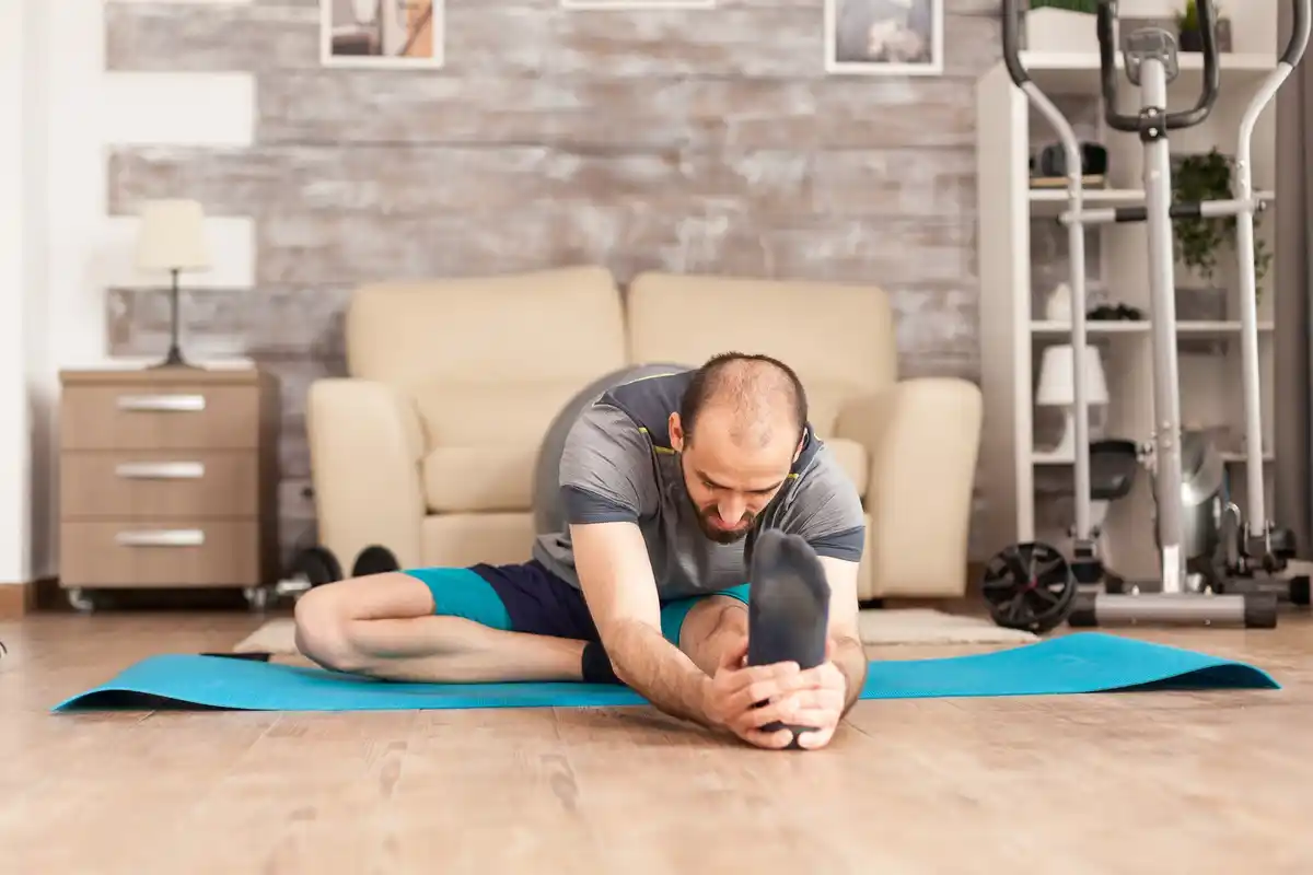 man doing stretching routine on rest day at home