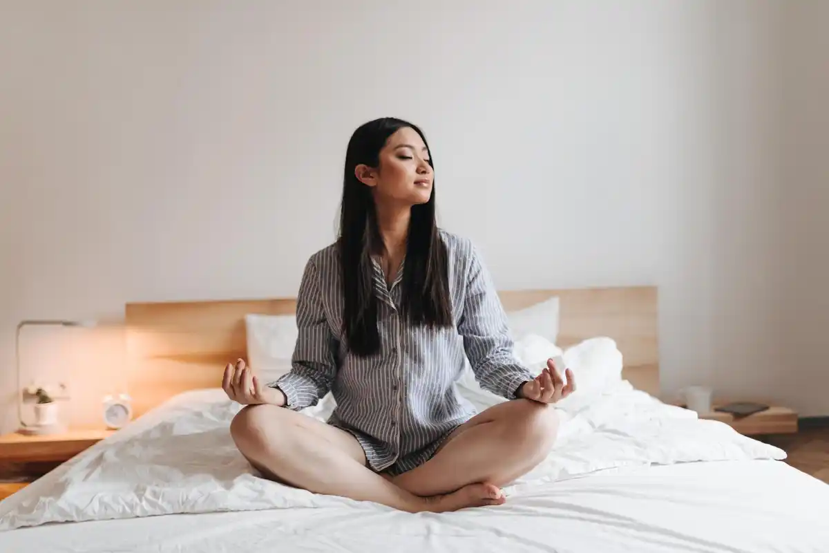 Dutch woman practicing yoga for sleep at night in cozy bedroom
