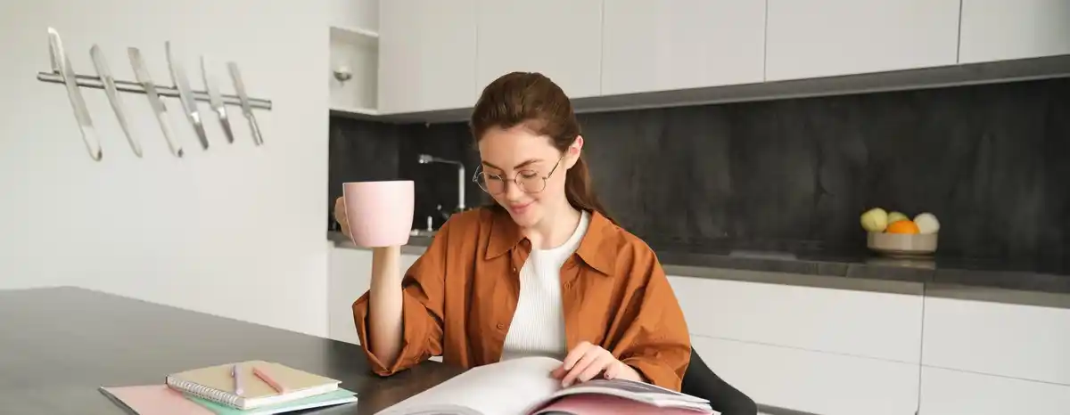 middle aged woman studying at home laptop notes coffee